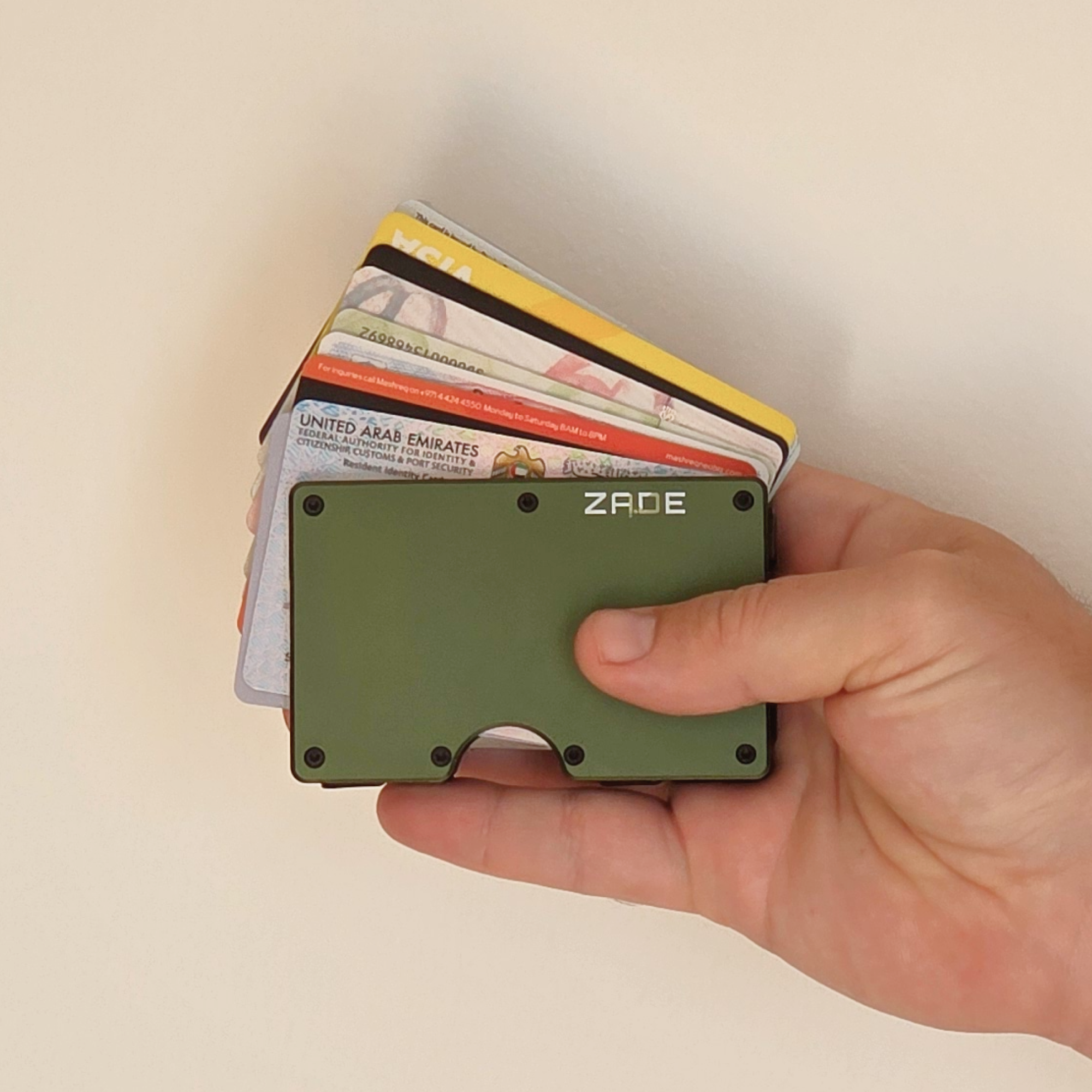 Zade olive green wallet held in hand with fanned out ID and bank cards
