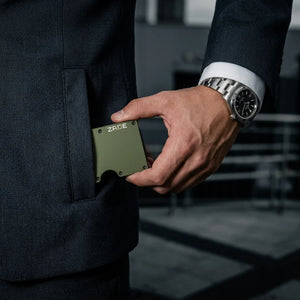 Zade olive green wallet placed into men's navy suit pocket with luxury watch